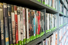 The image shows shelves filled with DVDs or books with green labels in Bend Oregon Last Blockbuster